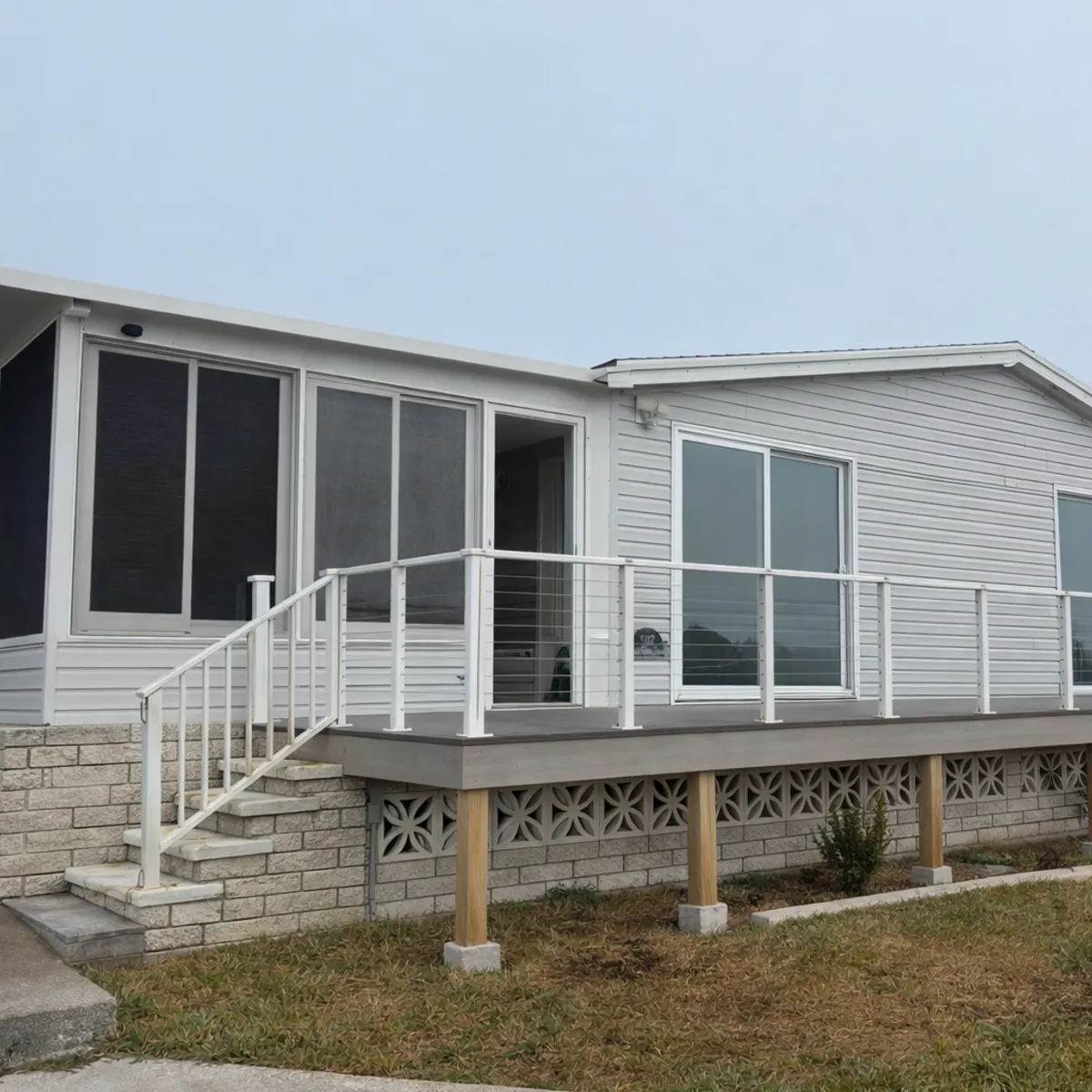 A deck with white cable railing and lattice skirting along a screened home